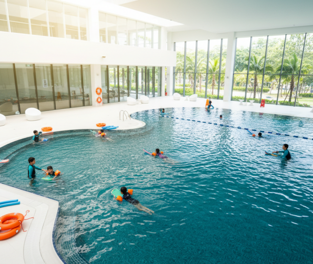 Modern Singapore pool with kids' lesson, turquoise water, tropical architecture, vibrant decor